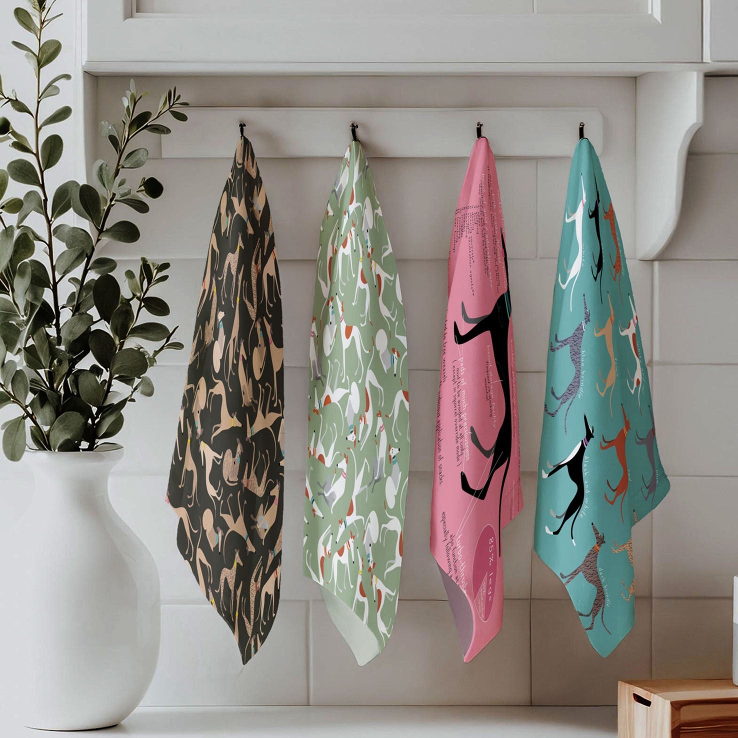 4 tea towels featuring hound prints hanging on 4 hooks in a minimalist white kitchen.