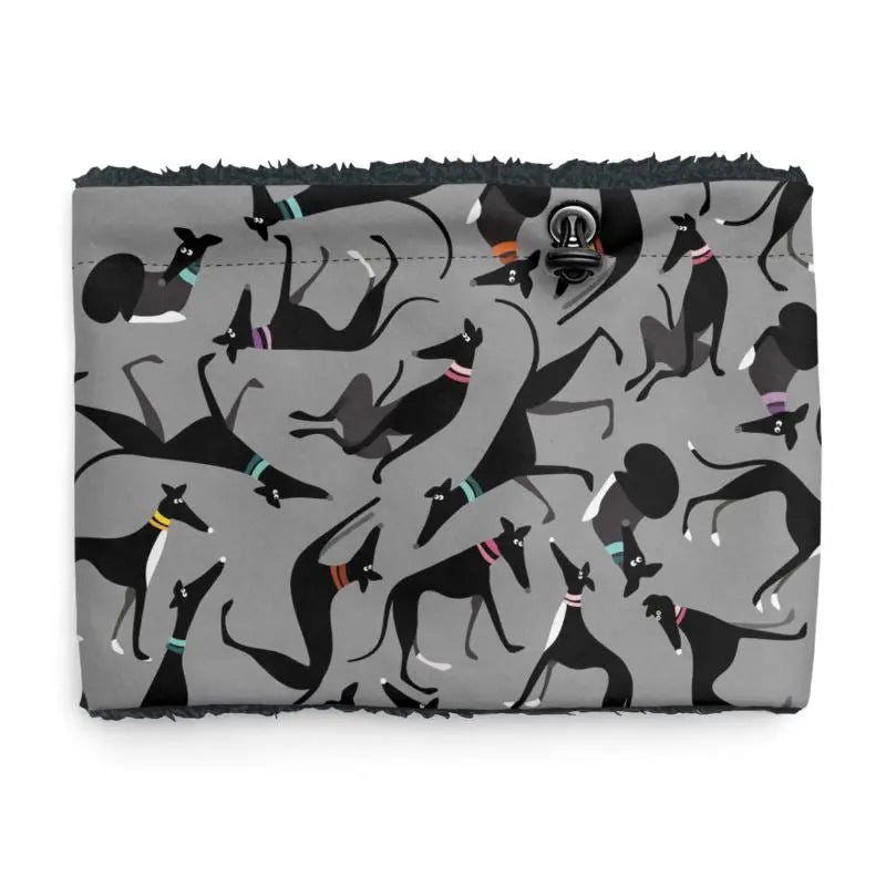 Front image of a sherpa fleece lined neck warmer with a grey background. The pattern on the outer is a repeat pattern of cute black and white greyhounds in various poses. There is an elastic pull cord with a toggle for size adjustment. The lining is black.
