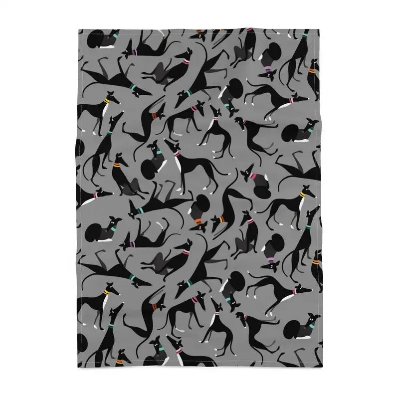 Tea towel with a grey backround. The repeat patterns shows lots of cute illustrations of black & White greyhounds in different poses.