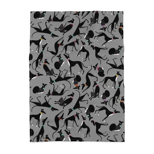 Tea towel with a grey backround. The repeat patterns shows lots of cute illustrations of black & White greyhounds in different poses.