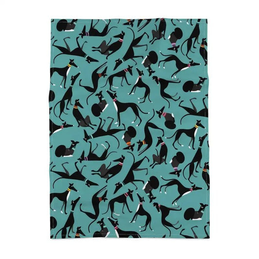 Tea towel with a turquoise backround. The repeat patterns shows lots of cute illustrations of black & White greyhounds in different poses.
