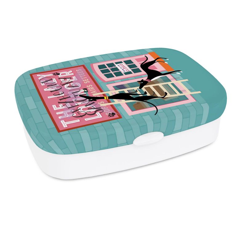 A lunch box. The base is white. The top has a full colour print wrapped around the sides. The background colour on the lid is turquoise. The image on the lid shows the front of a sofa shop called the Lazy Lounger. It is currently closed. There is a greyhound standing up a ladder with a paintbrush in their mouth. They have painted 'Greyhound Sanctury' over the top of the shop sign. There is a 2nd greyhound keeping watch.