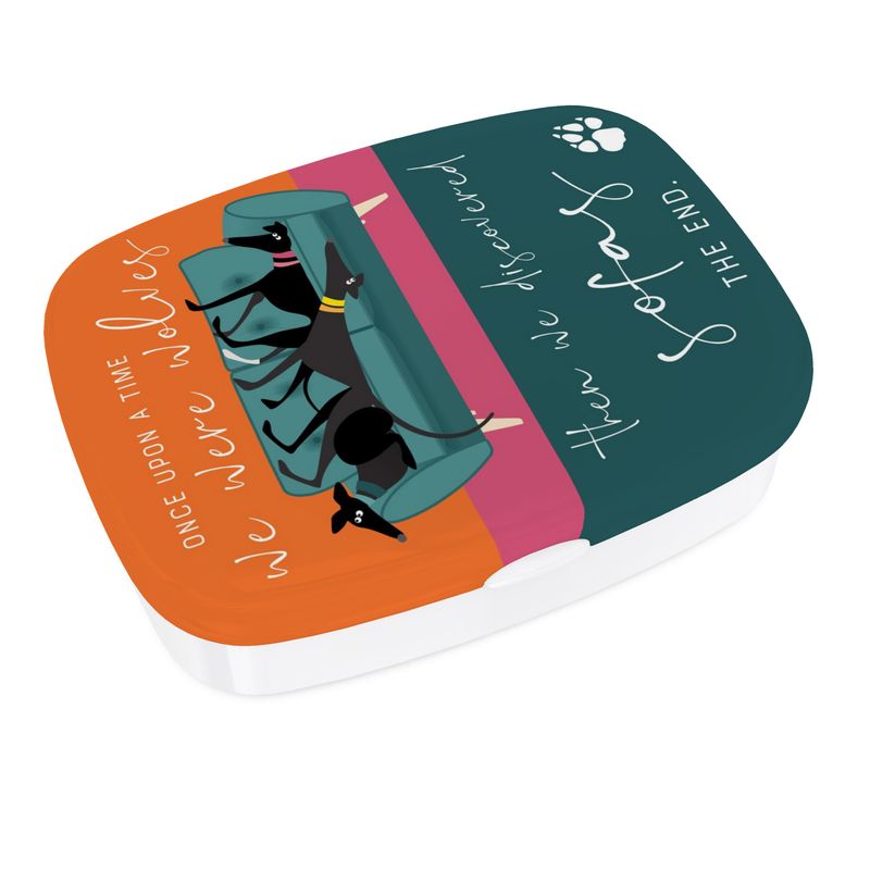 A different view of the lunch box. The base is white. The top has a full colour print wrapped around the sides. The background colour on the lid is turquoise, pink & orange. On the lid is an illustration of 3 greyhounds on a 2 seat teal sofa. Around the illustration the text reads; Once upon a time we were wolves. Then we discovered sofas. The End.